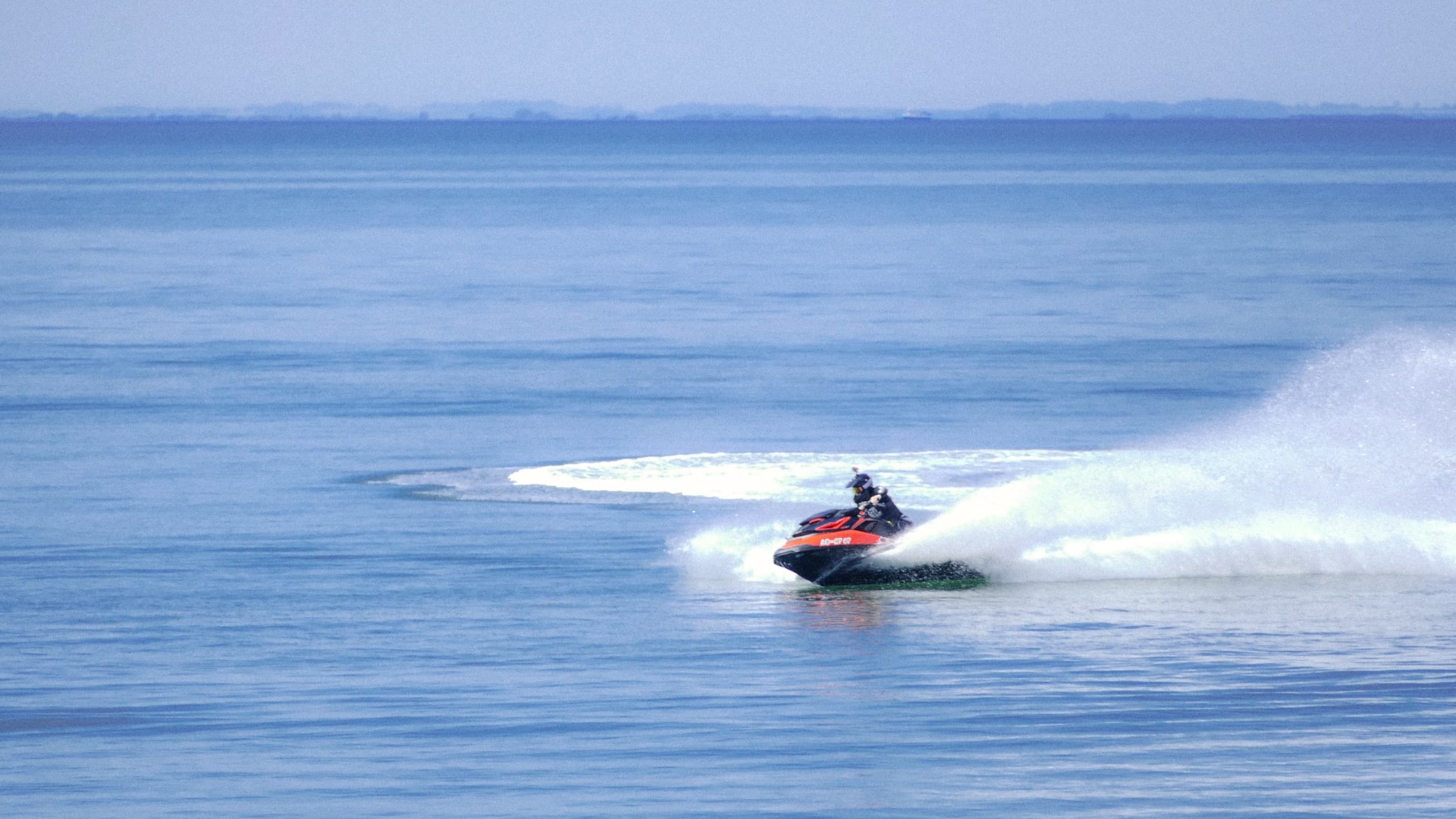 PWC carving wide calm blue sea, scenic offshore personal watercraft