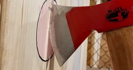 Axe thrown into wooden target at indoor axe throwing range