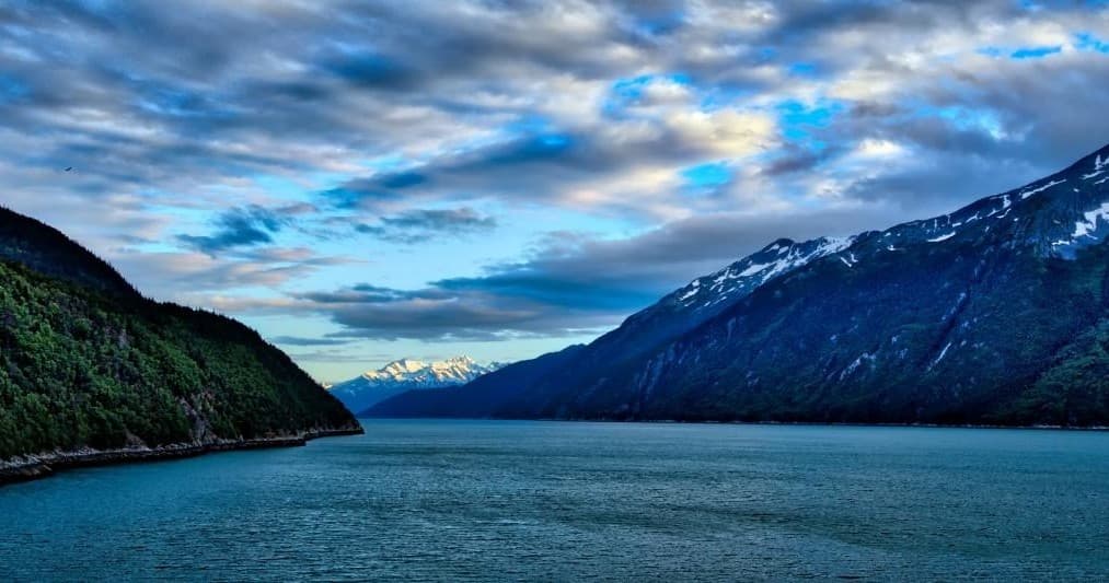 Scenic mountain fjord and glacier inlet under dramatic sky