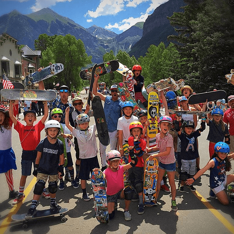 Large youth skate crew posing outdoors in mountain town