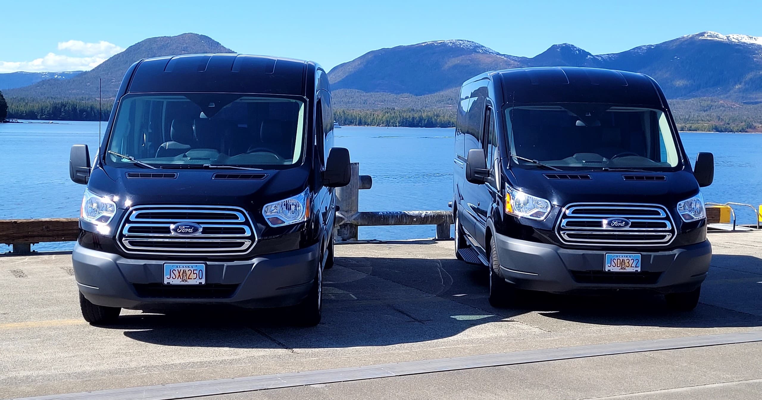 Tour vans parked waterfront with mountain views in Alaska