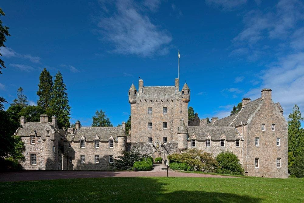 Stone castle courtyard and manicured lawn under blue sky