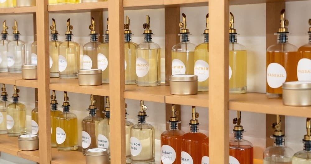 Candle-making fragrance bottles arranged on wooden shelves in Dallas studio