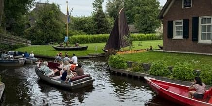 Guided boat tour through narrow Dutch canal past village homes