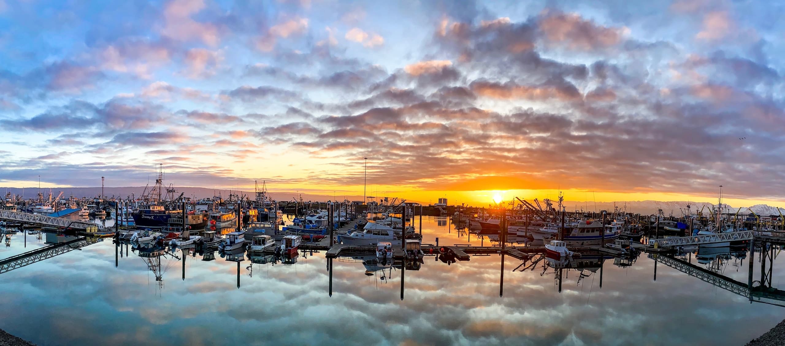 Sunset over Alaska marina with charter boats and reflections