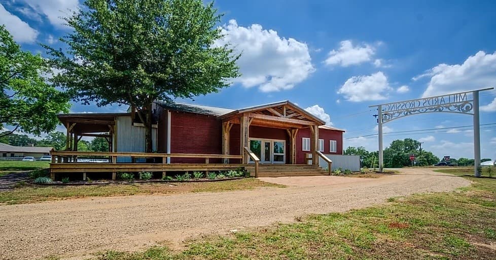 Ranch-style country building with porch and wide dirt road