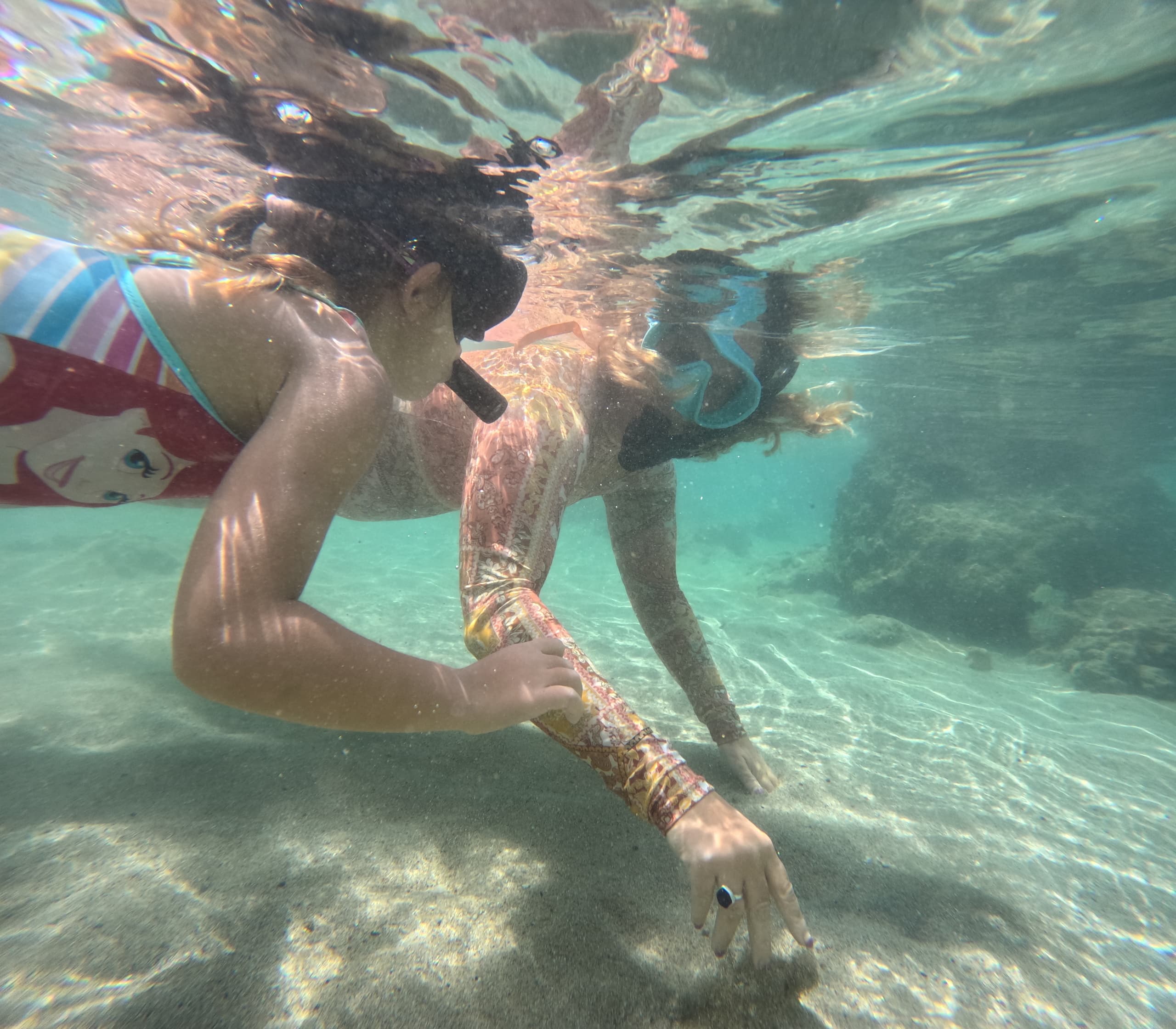 Children snorkeling under shallow Hawaiian bay exploring coral