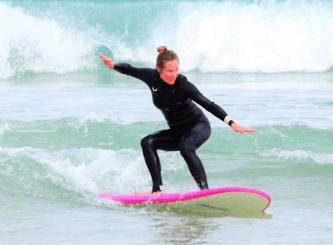 Surfer riding small shore break on pink board at Mandurah beach