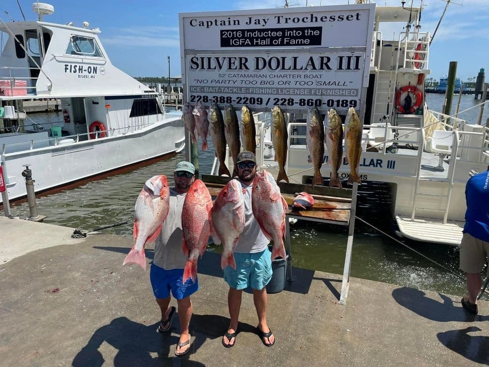 Anglers holding large red snapper at marina dock after charter