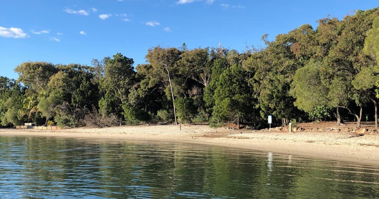 Relaxing sandy shoreline viewed from ferry on calm harbor