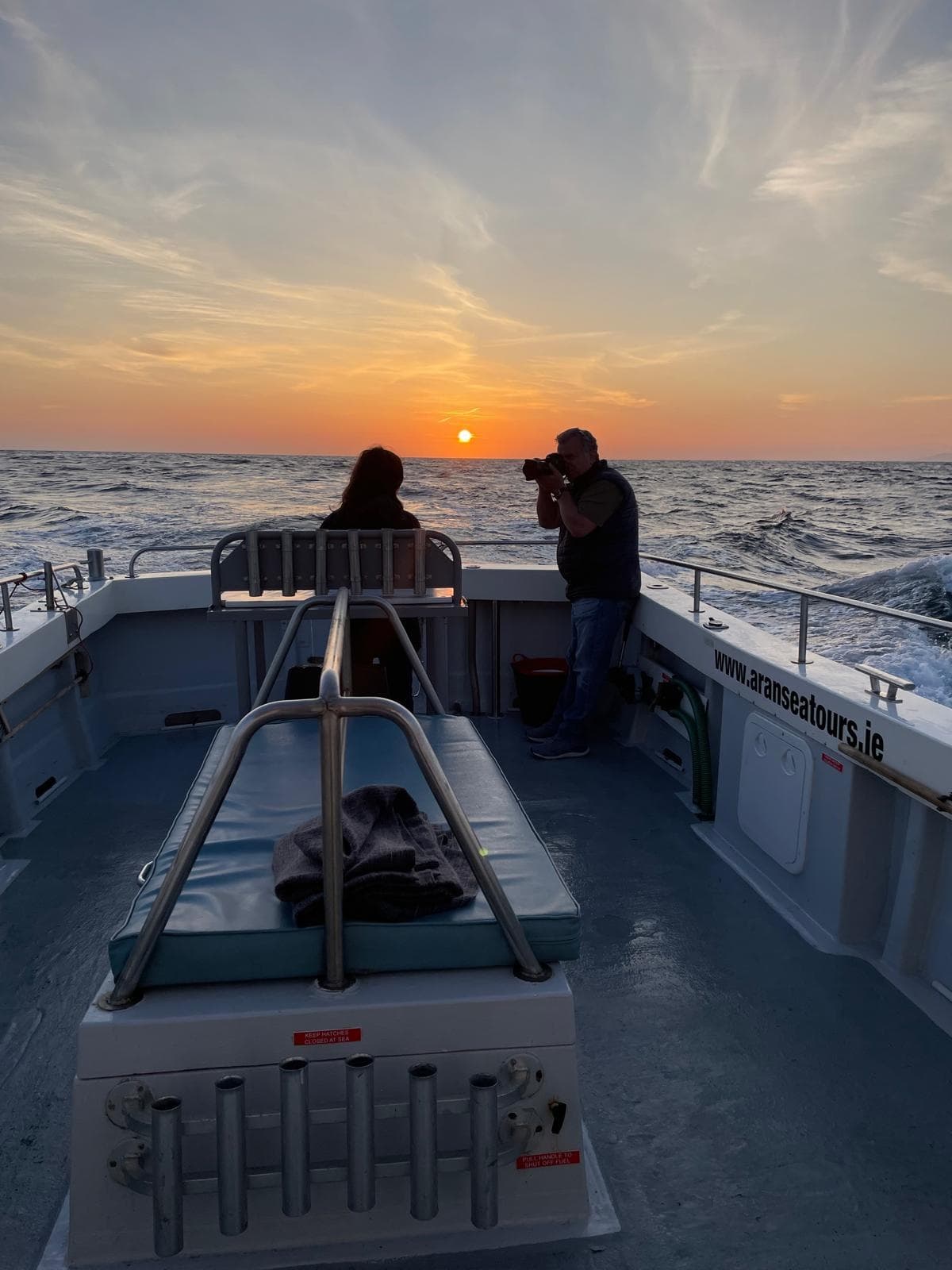 Sunset boat tour on choppy sea with photographer capturing sunset