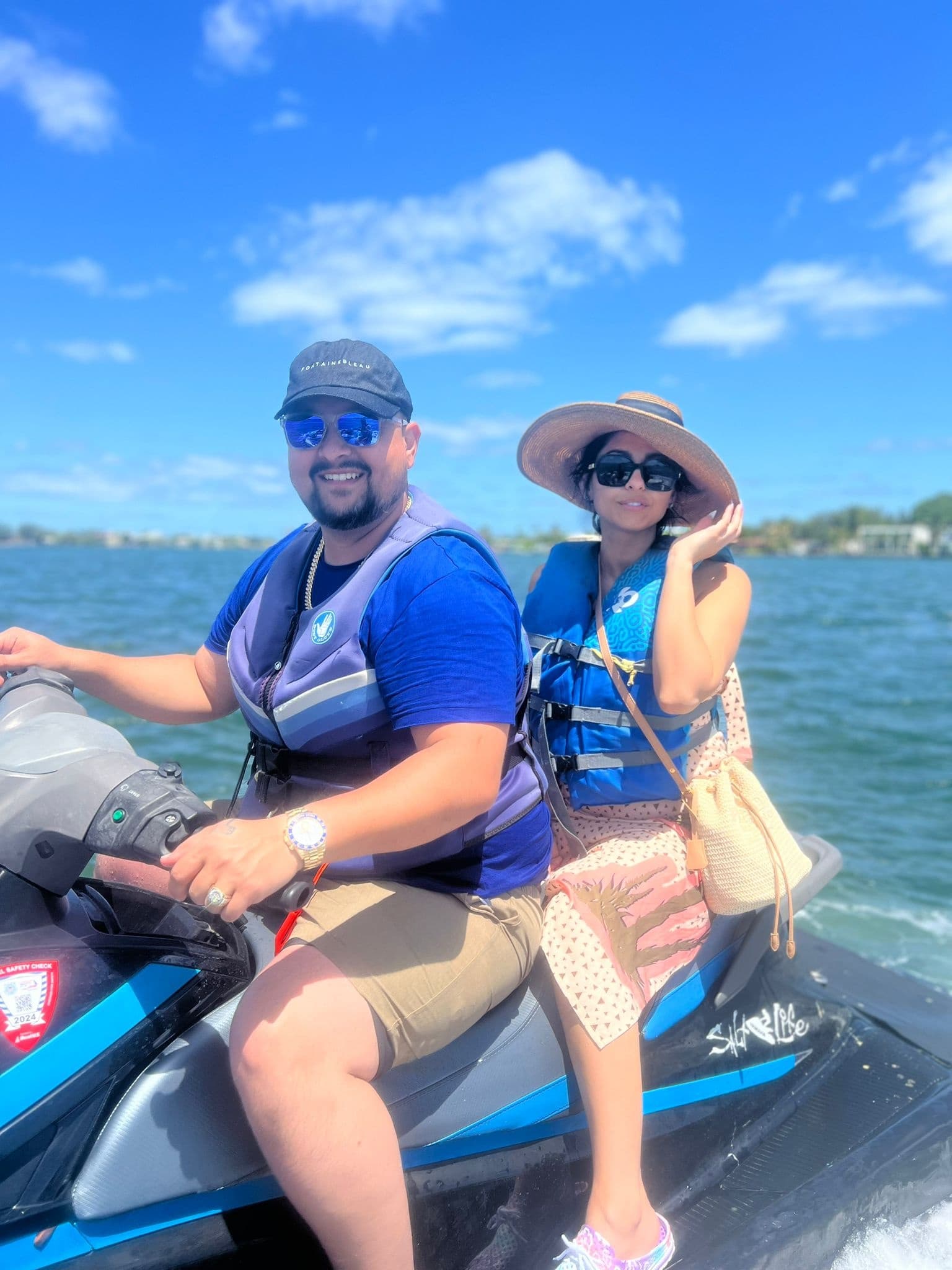 Couple riding jet ski on sunny coastal waters near shoreline