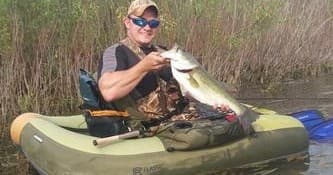 Kayaker holding large fish in marshy Hocking Hills river