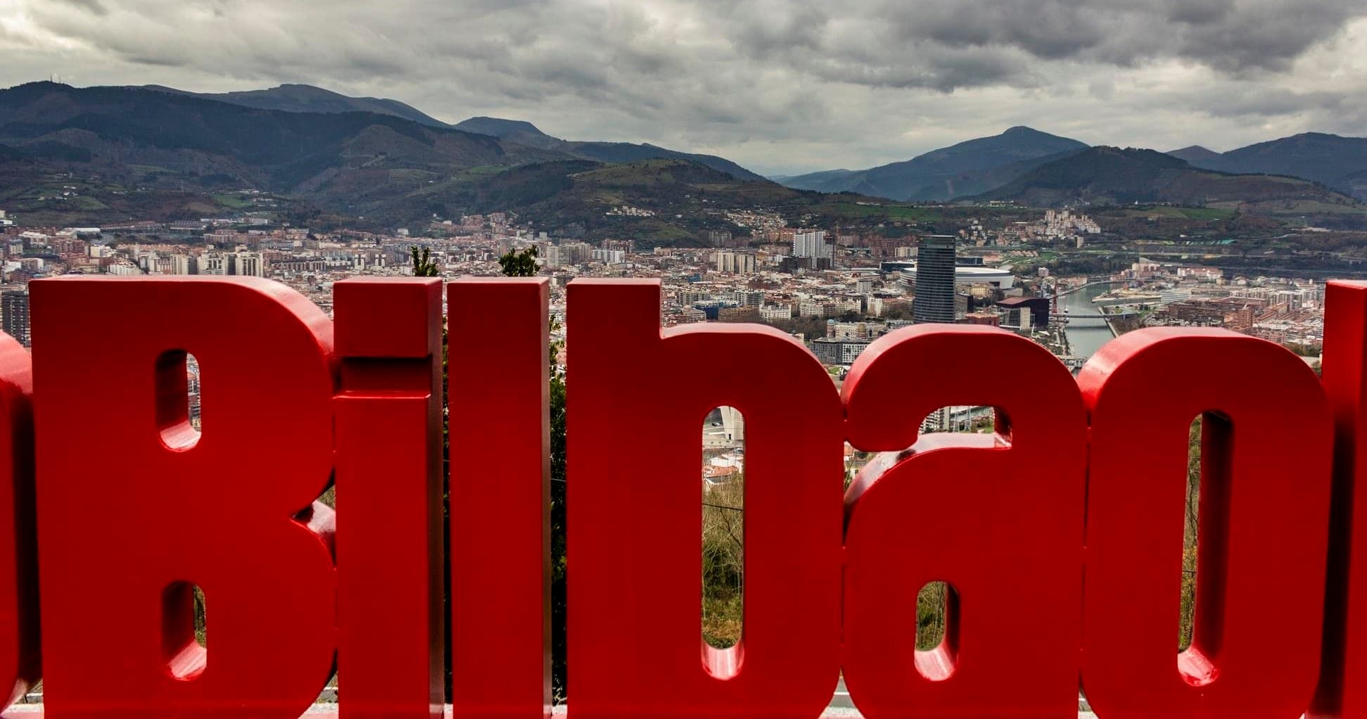Red 'Bilbao' letters sign overlooking city, popular photo spot