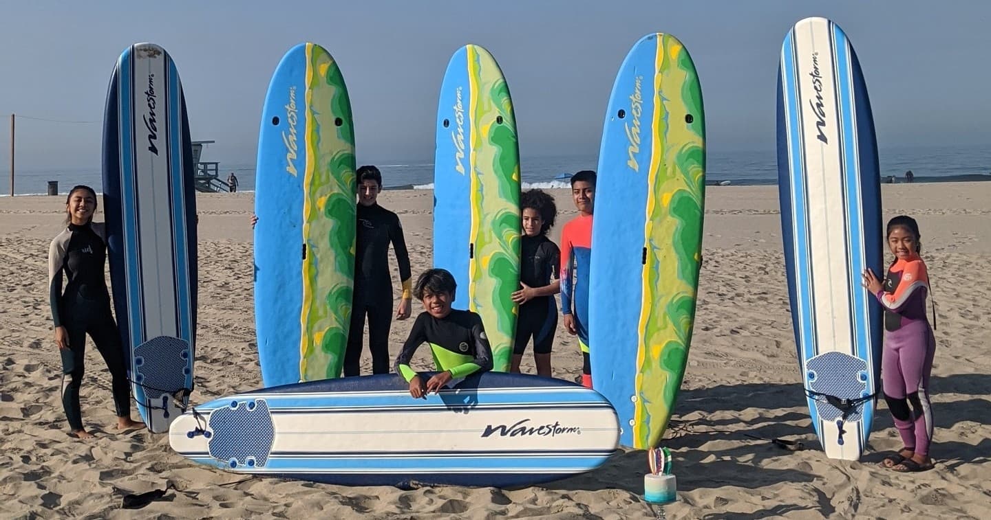 Surf lesson group standing by surfboards on the beach