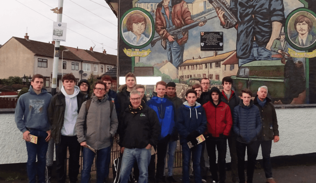 Walking tour group in front of political mural on city street