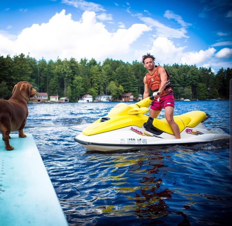 Man on yellow Jet Ski launching from dock with dog nearby