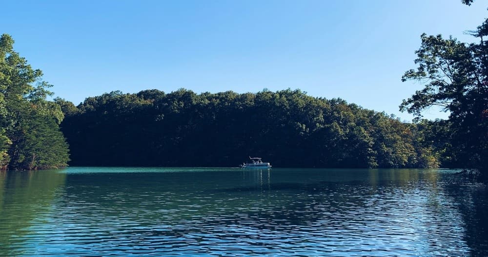 Small boat on calm lake with forested shoreline, scenic view