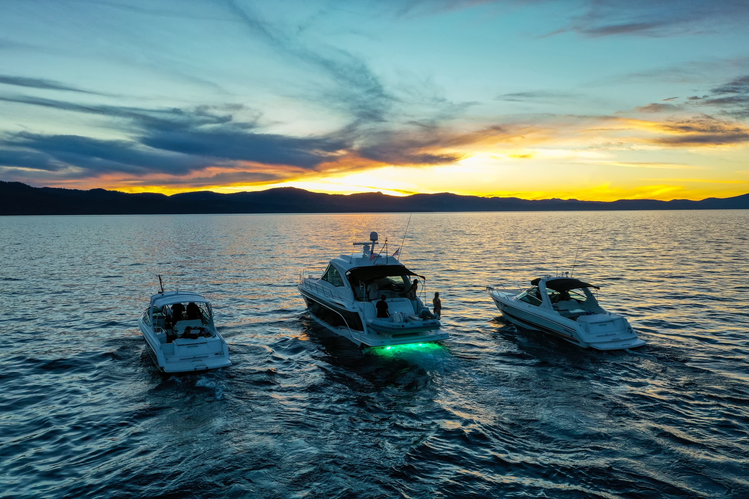Three luxury boats cruising at sunset on Lake Tahoe