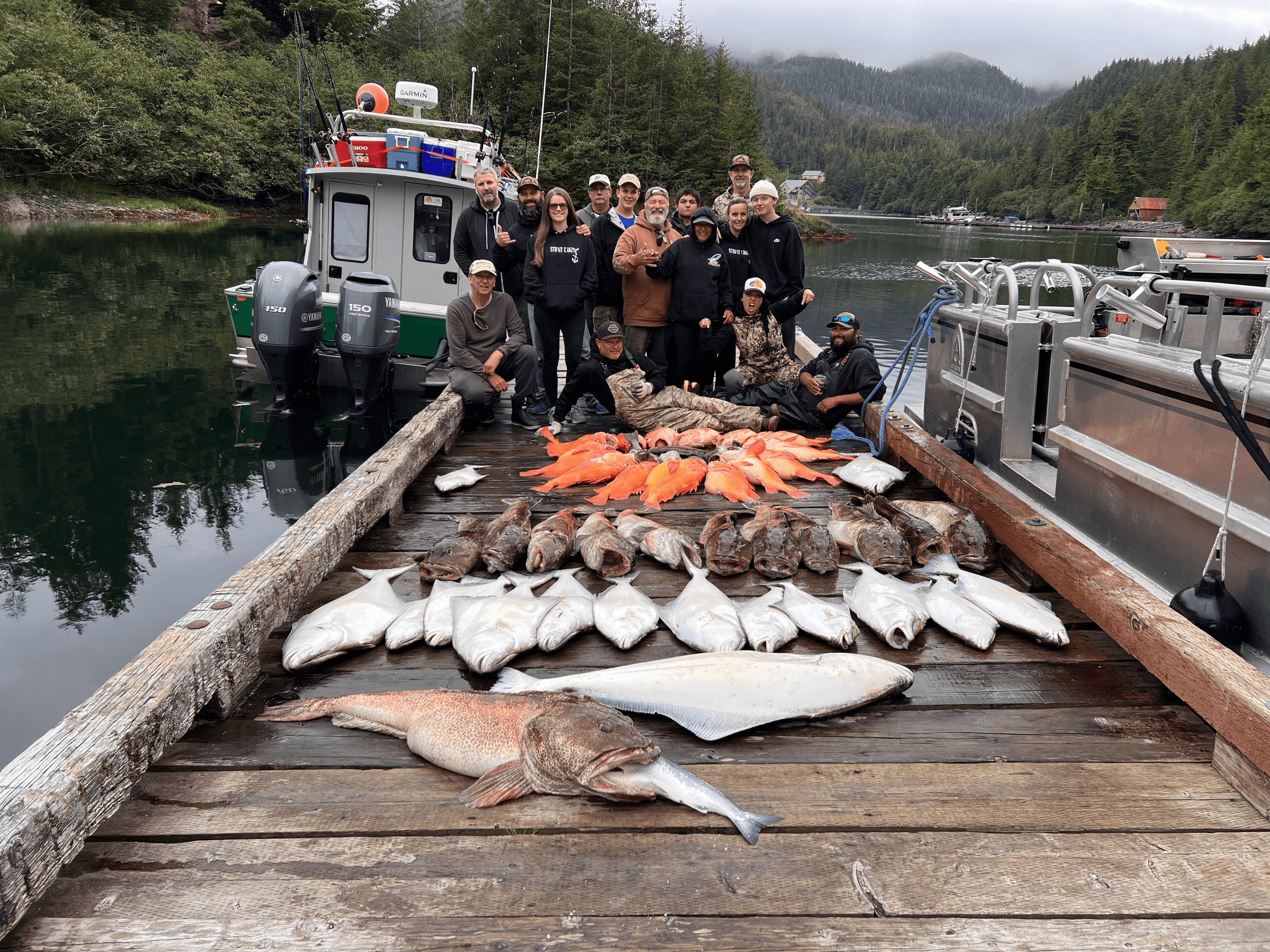 Group of anglers with large catch on dock beside fishing boats