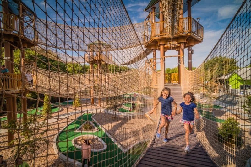 Wooden aerial ropes walkway with visitors at outdoor course