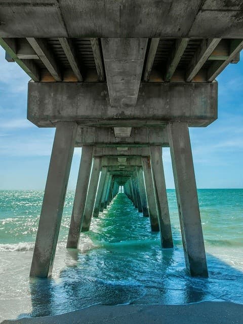 View beneath concrete pier over turquoise sea, dramatic perspective