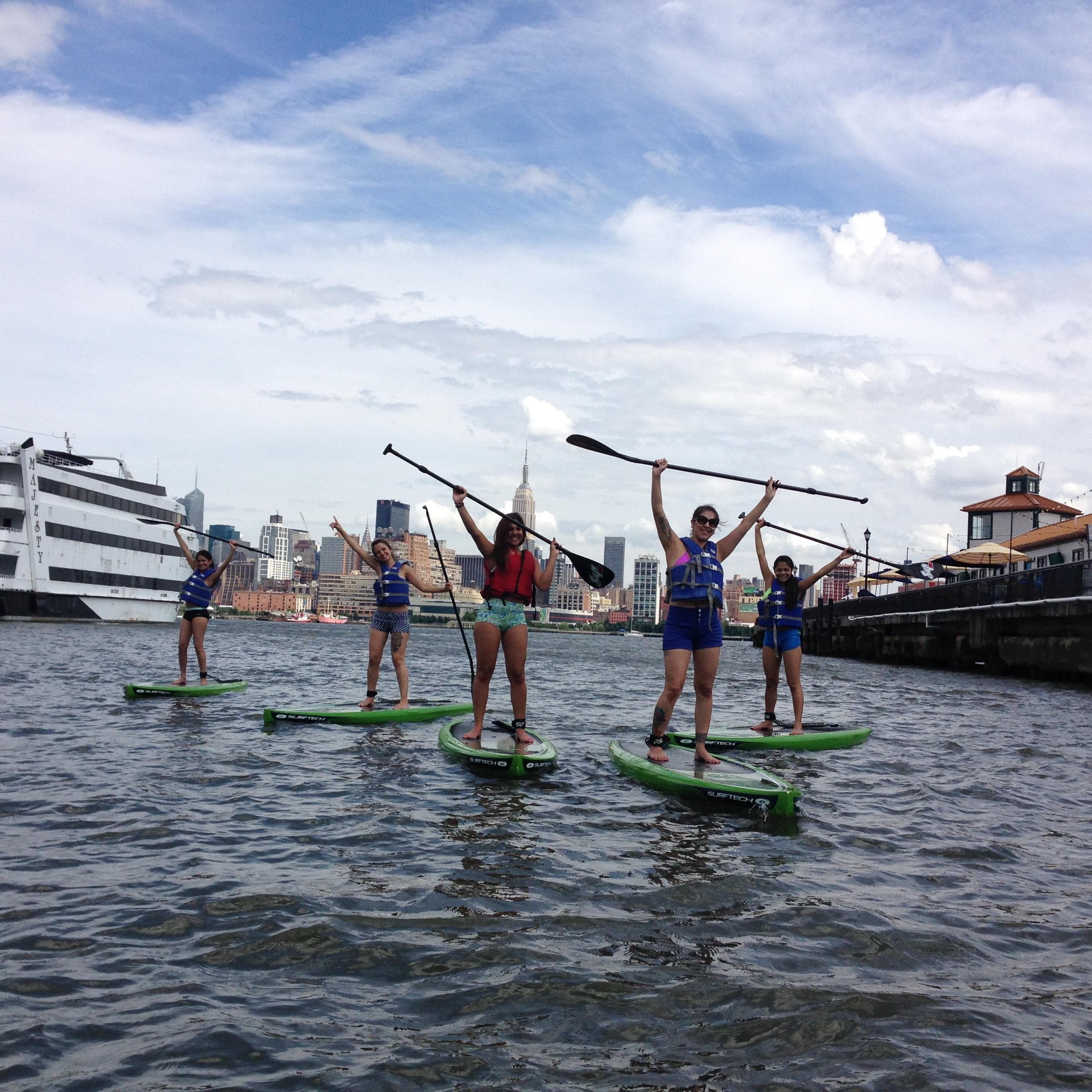 Two kayakers smiling with New York skyline behind them