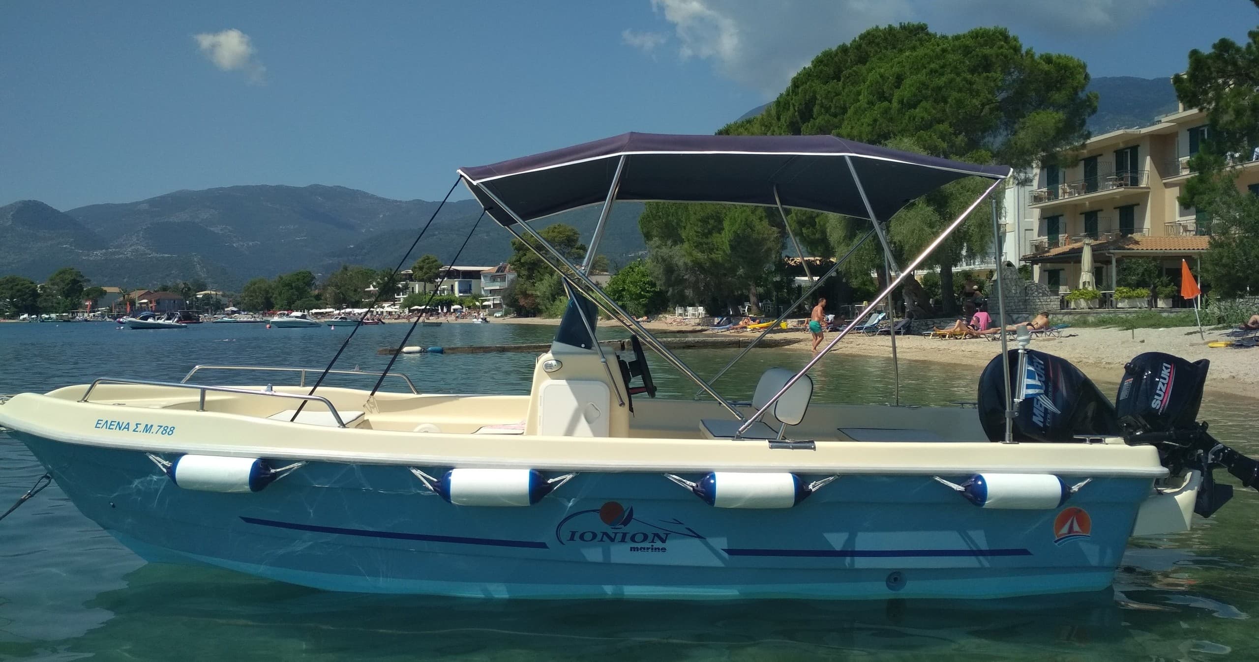 Coastal rental boat with canopy cruising calm Ionian bay waters