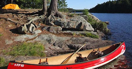 Couple portaging canoe through rocky trail in Algonquin Park