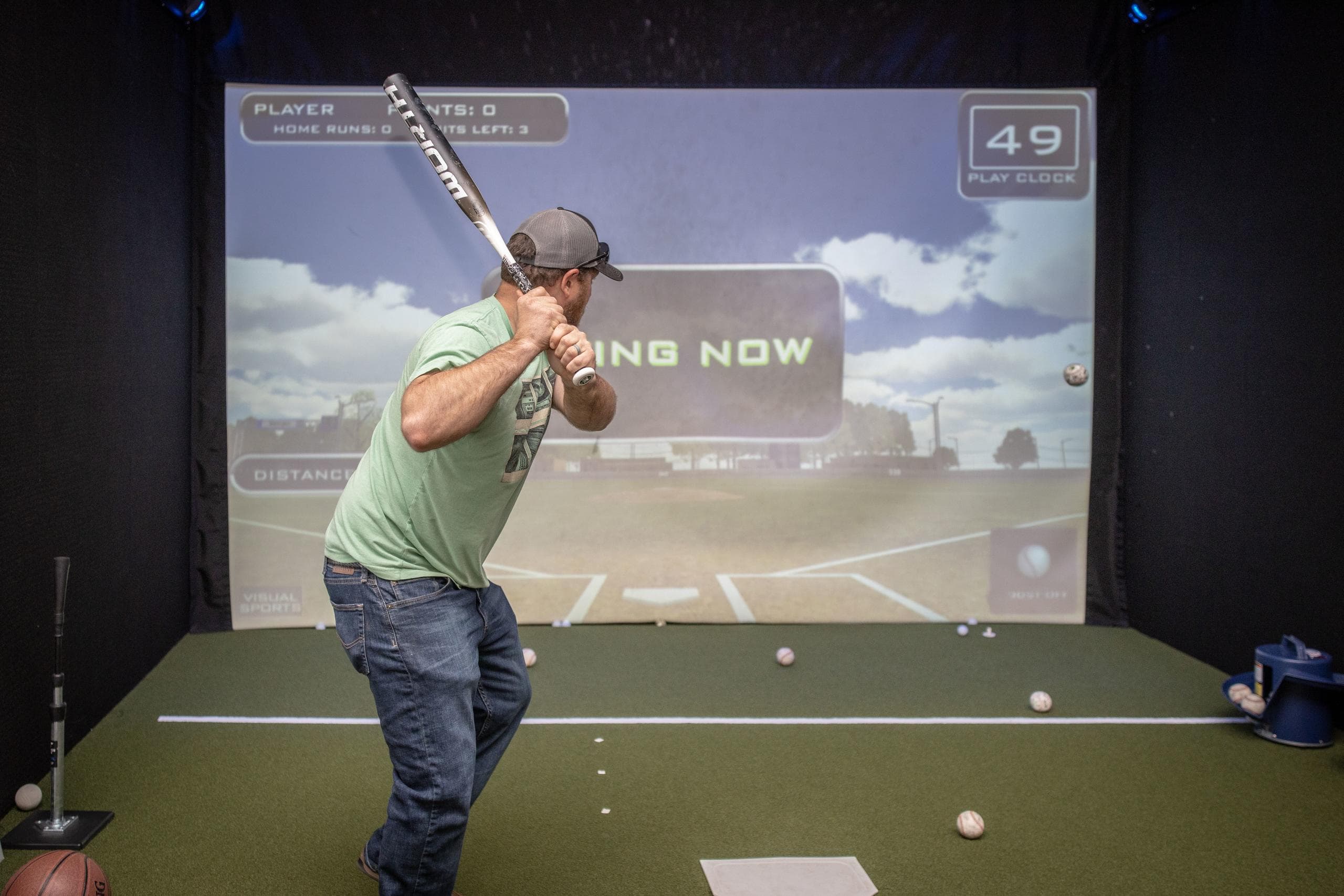 Man swinging driver in indoor golf simulator practice stall