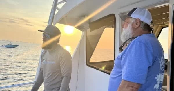 Crew members watching sunrise from charter boat deck