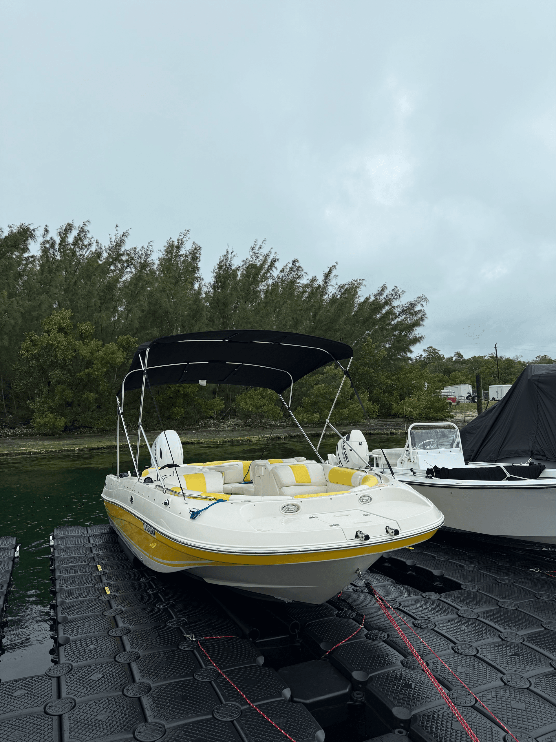 Yellow bowrider boat moored at dock under cloudy skies, waterfront