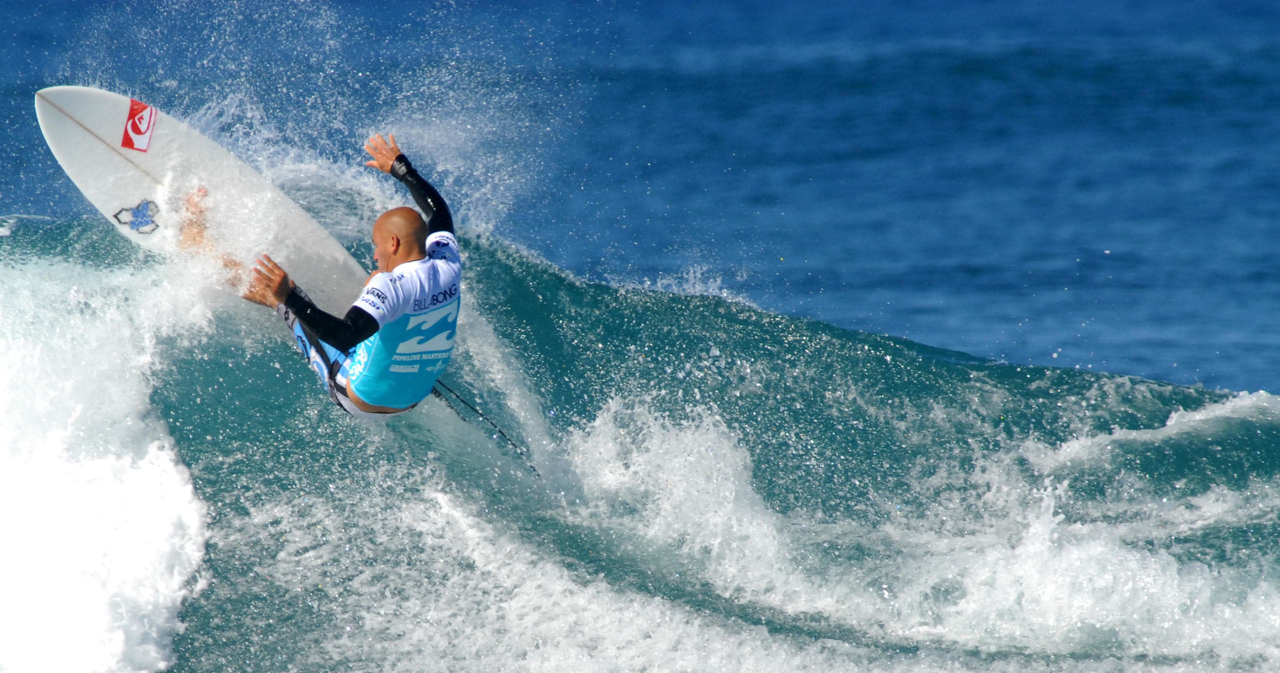 Competitive surfer aerial maneuver on Pacific reef wave
