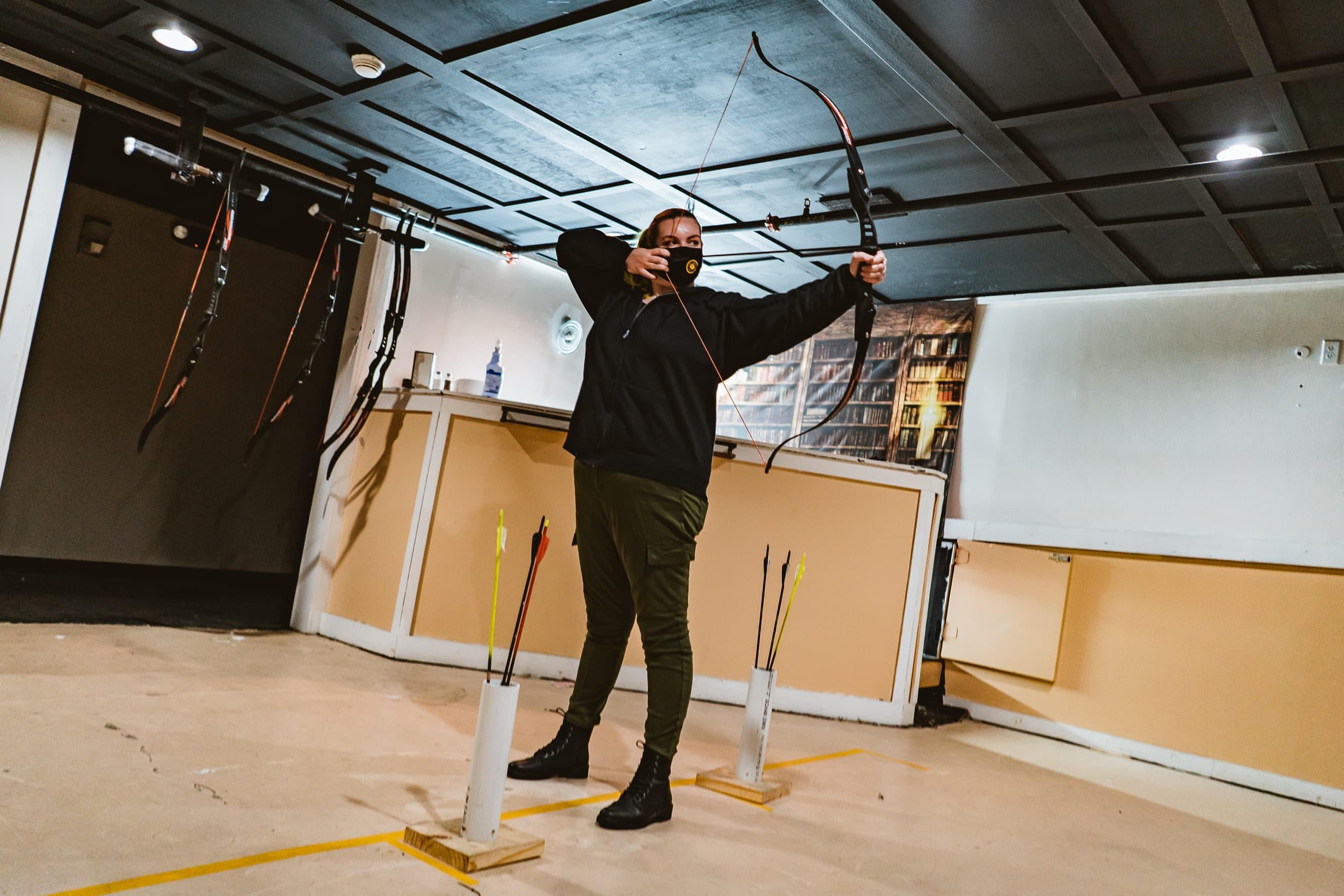 Archer drawing a bow at an indoor archery range in Syracuse