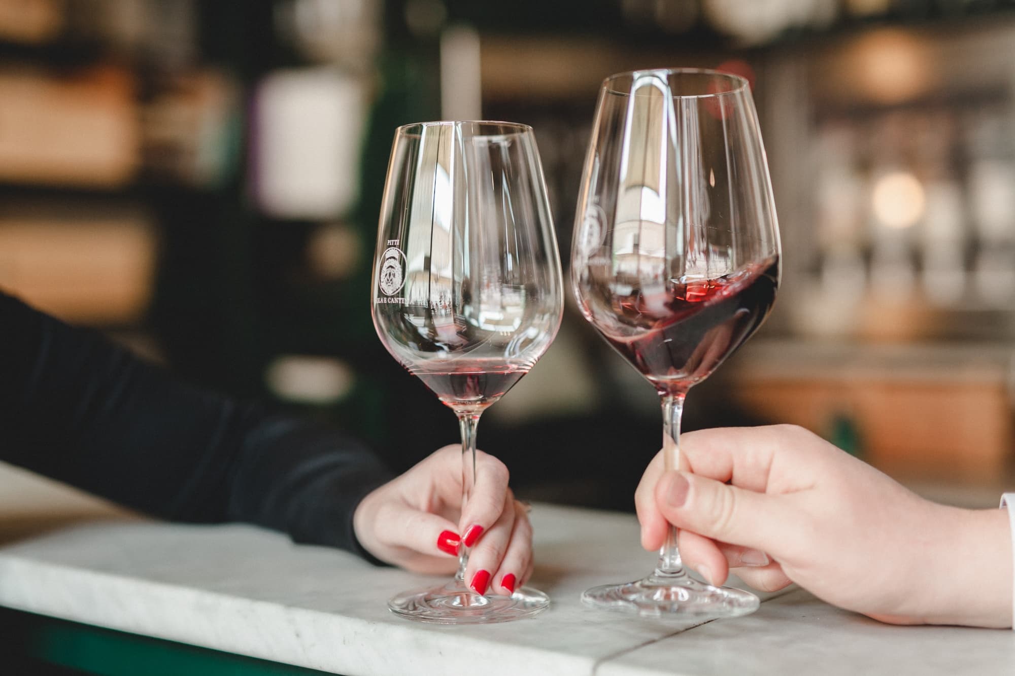 Two people toasting red wine at indoor wine bar in Florence