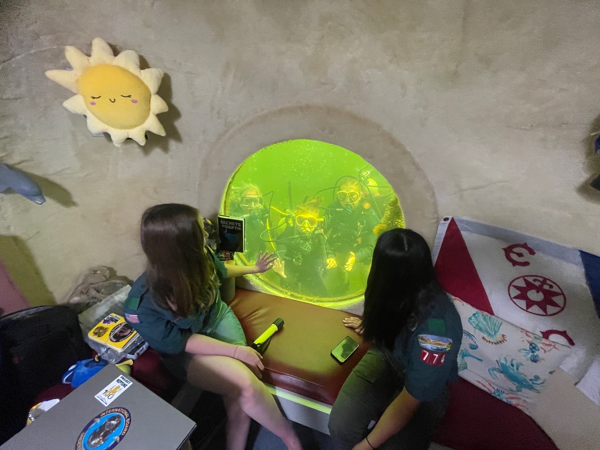 Children inside underwater observatory room peering through porthole