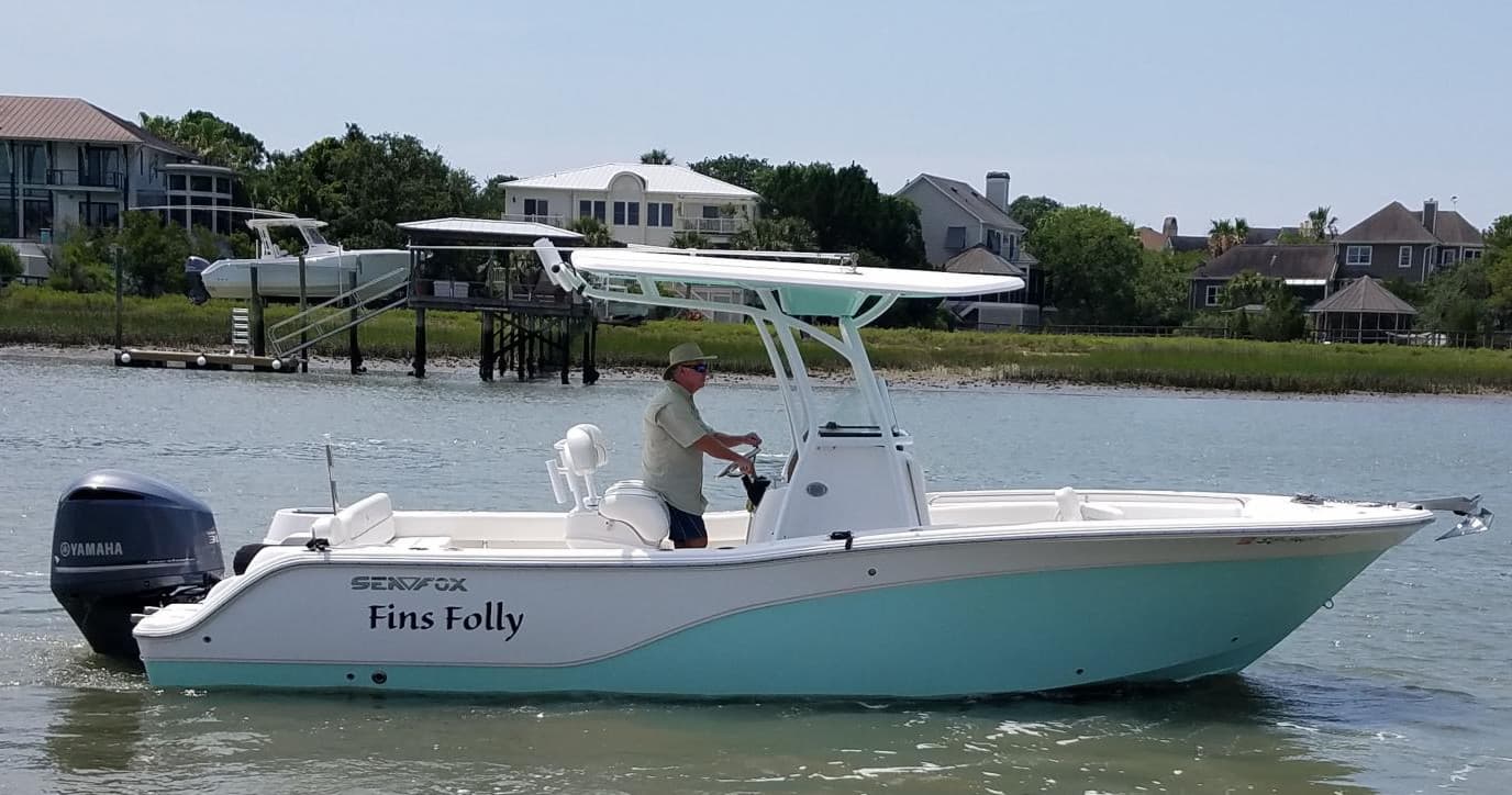 Coastal center-console boat with captain cruising near homes