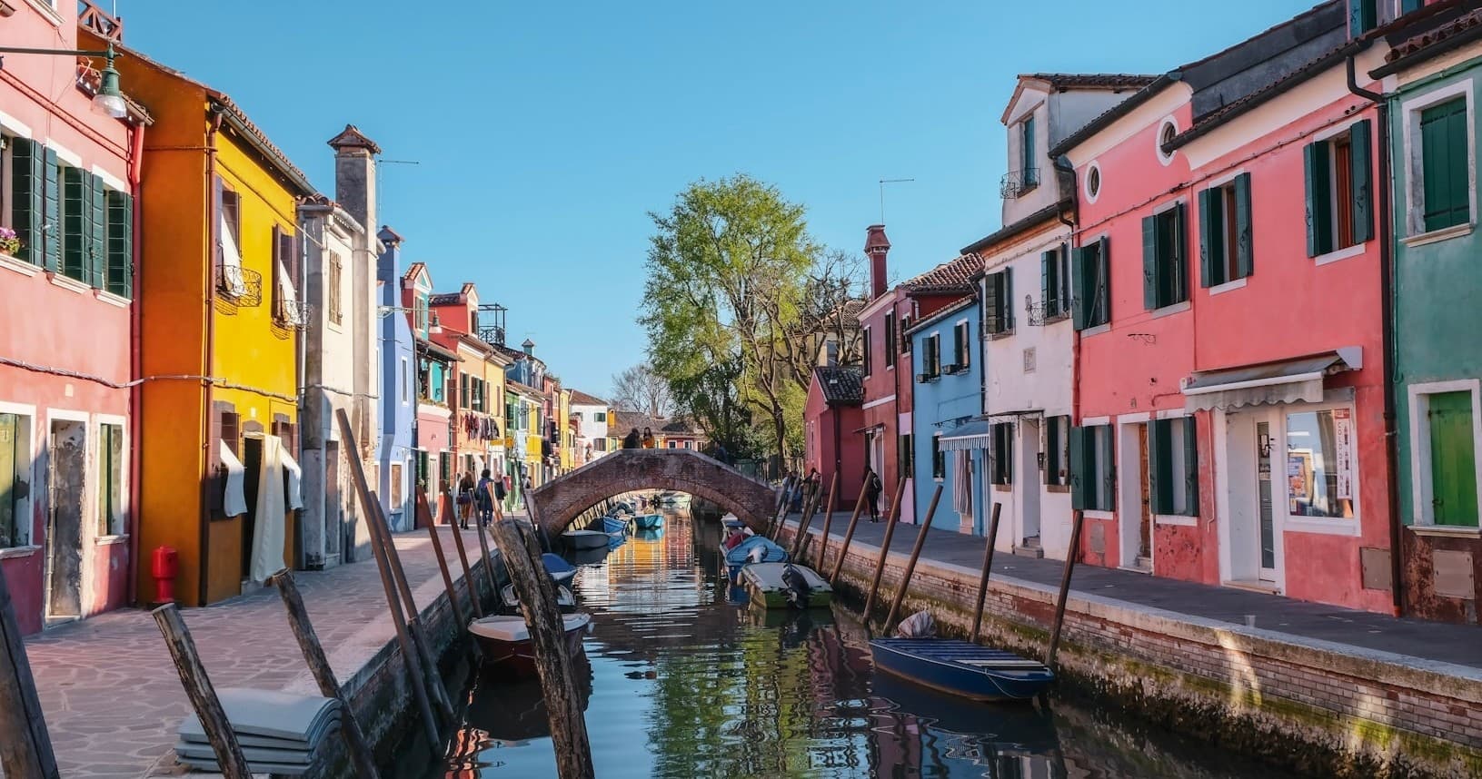 Colorful canal boats cruising Burano island canal, Venice