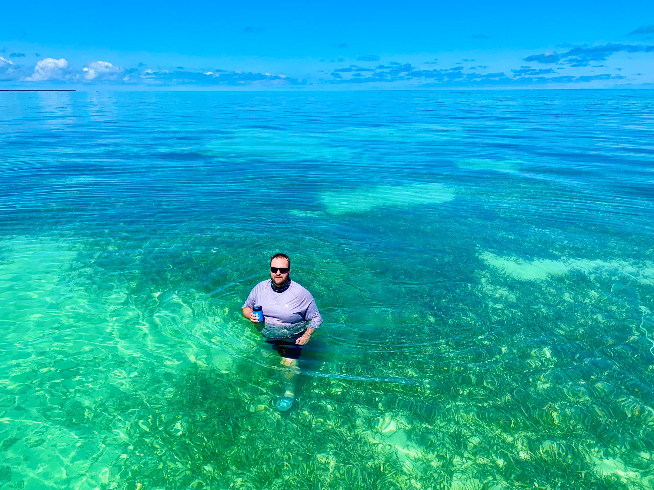 Man standing in crystal turquoise ocean waters, snorkeling spot
