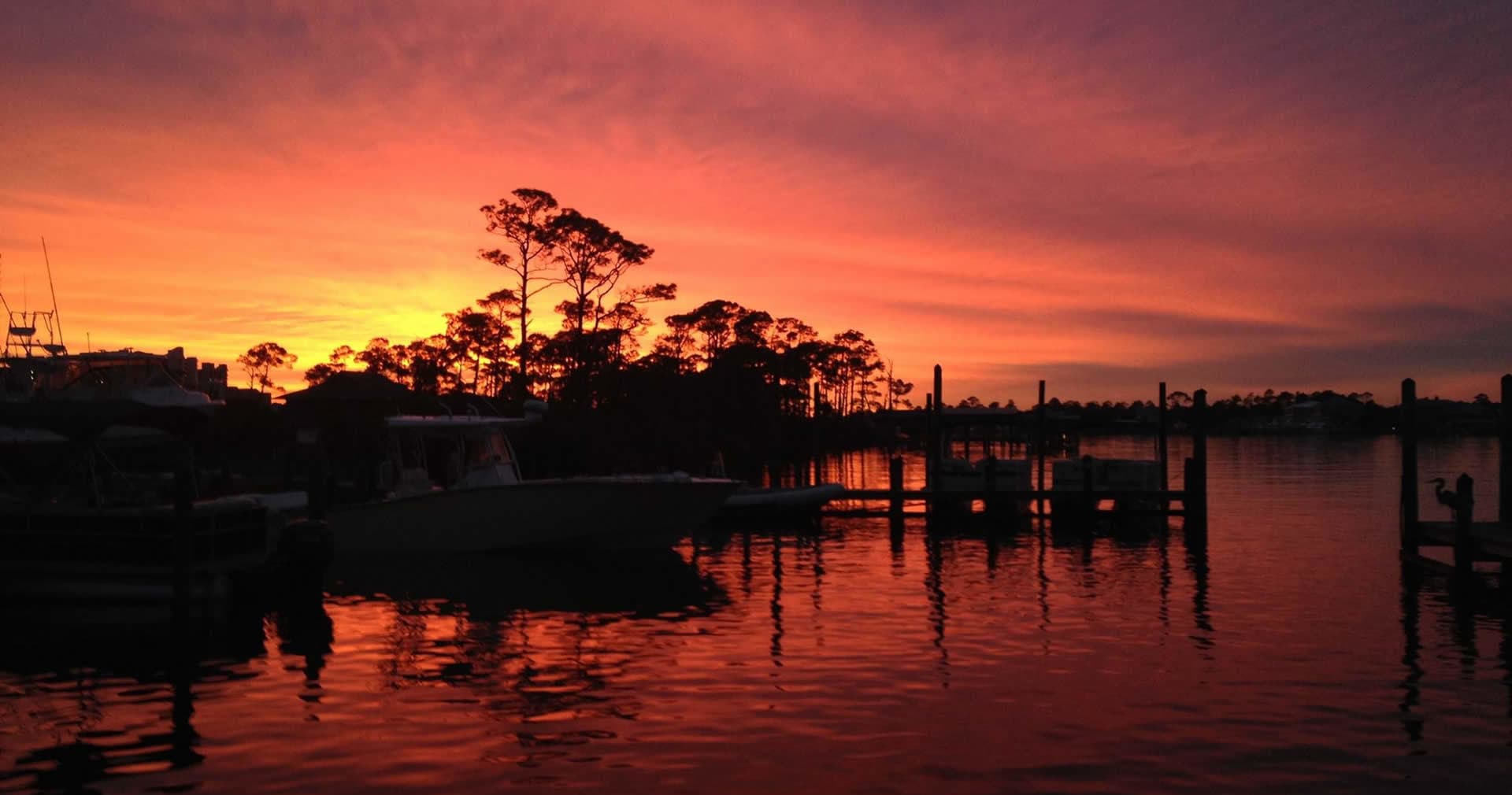 Sunset over marina silhouette with boats on reflective water