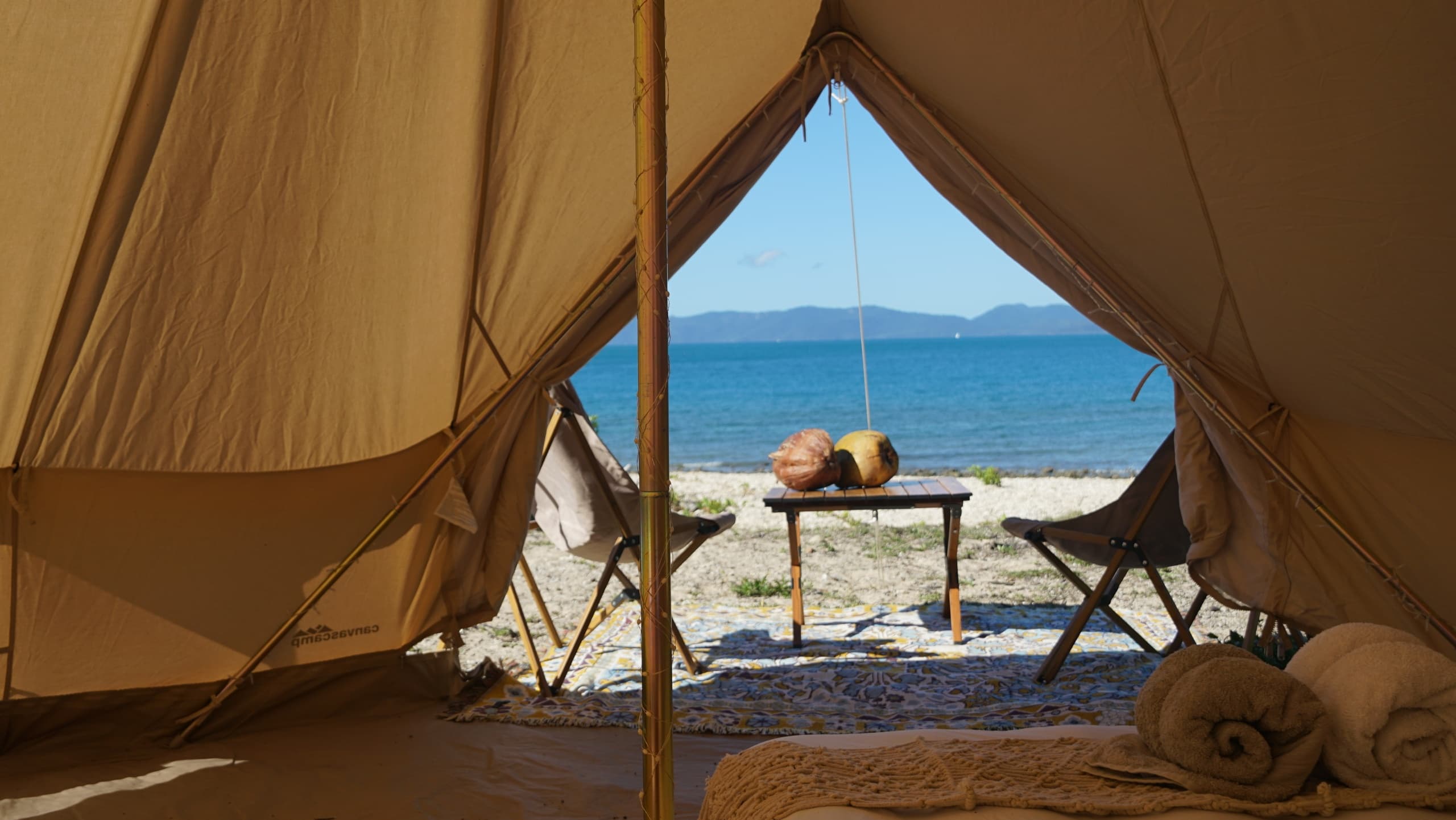 View from tent interior opening to pebble beach and turquoise sea