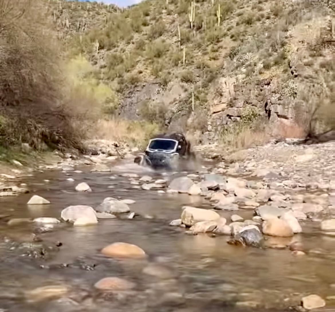 Off-road UTV splashing through rocky desert stream crossing