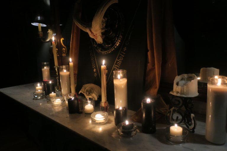 Candlelit ritual altar indoors, occult exhibit setting