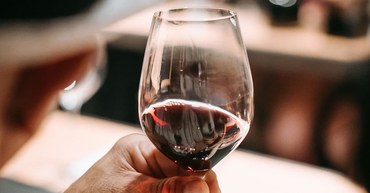 Hand holding red wine glass at intimate tasting table