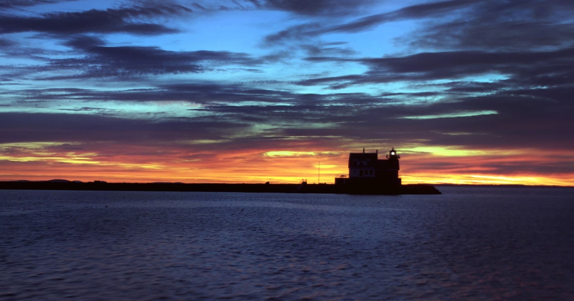 Sunset silhouette of island and distant vessel on ocean horizon
