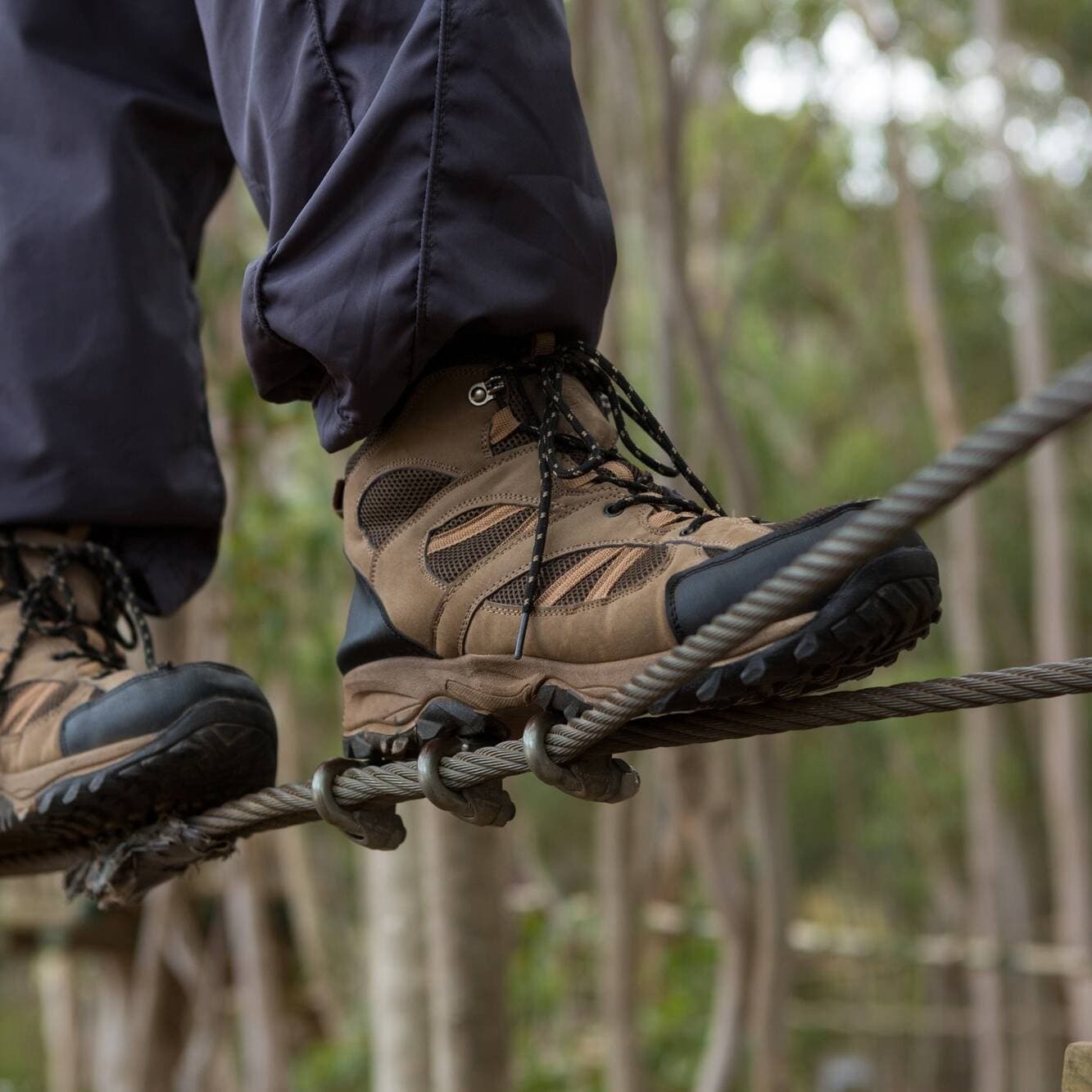 Close-up high ropes course boots balancing on forest rope