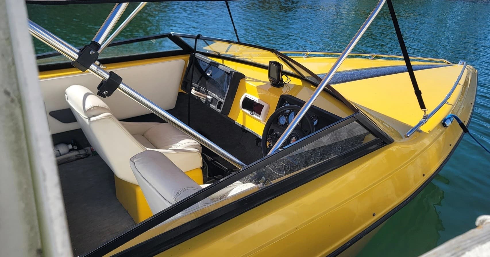 Interior of yellow speedboat docked at quiet lakeside pier