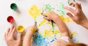 Kids and adults fingerpainting together on studio table activity