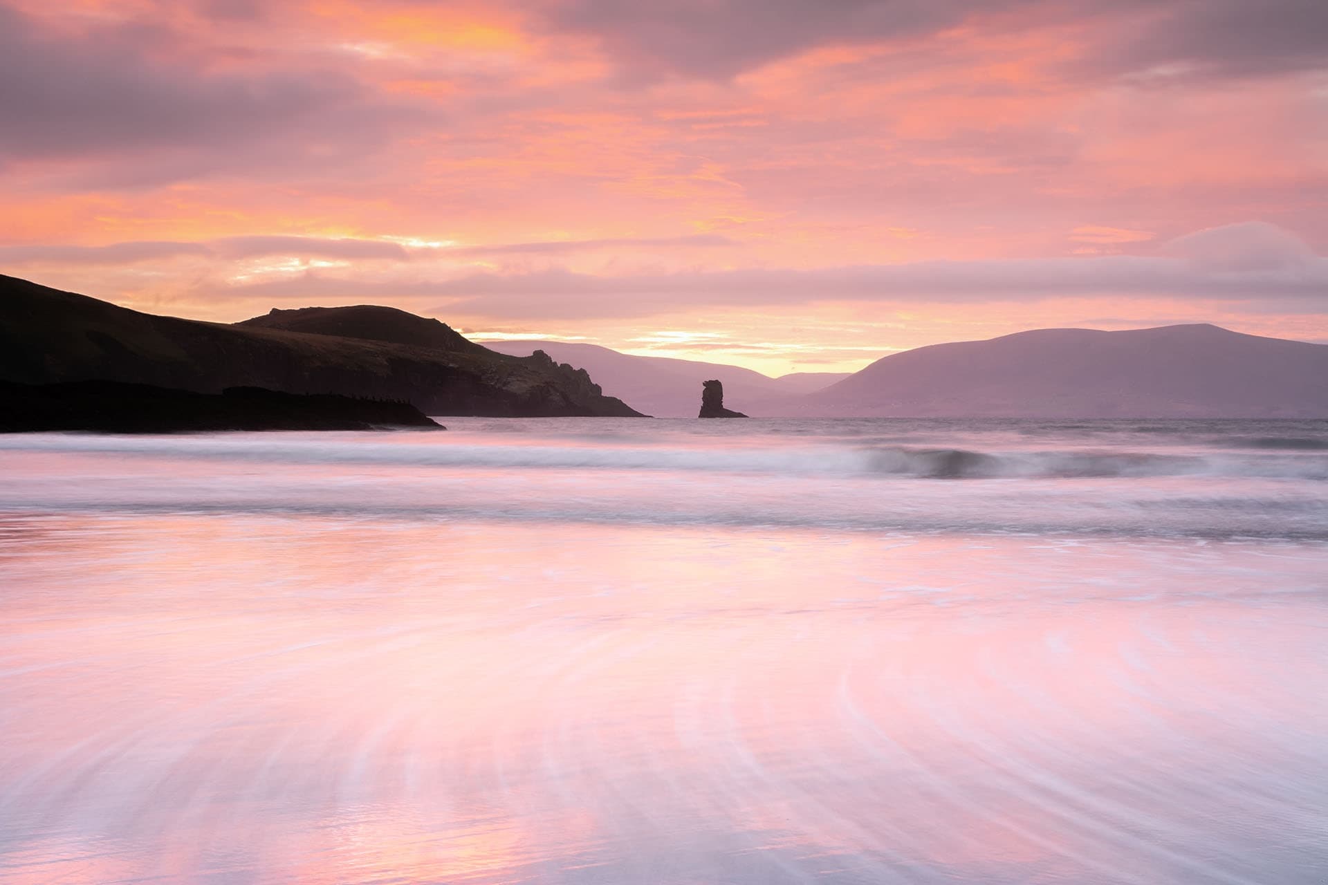 Pastel long exposure beach at sunrise with smooth pink sand reflections