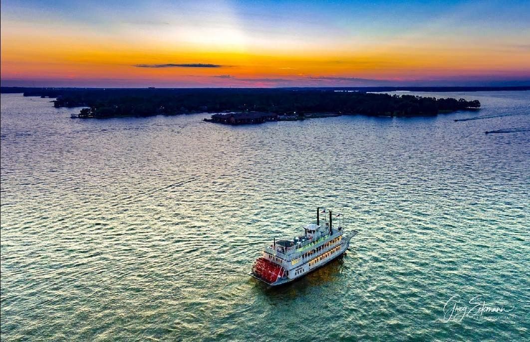 Aerial riverboat cruising at sunset over open-water vistas